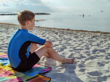 Rear view of boy sitting on beach