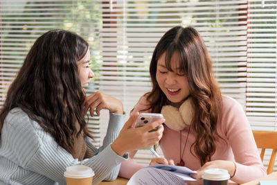 Young woman using mobile phone while sitting on table at home
