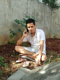 Young man looking away while sitting on land