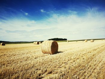 Hay bales on field against sky