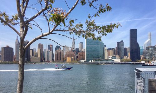 Boat in east river by cityscape against sky