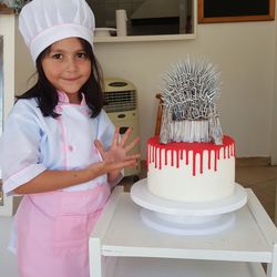 Portrait of girl in chef white standing by cake at home