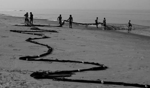 People with fishing net at beach against sky