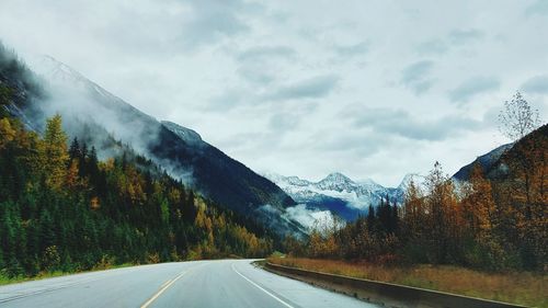 Road by snowcapped mountains against sky