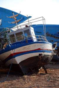 Fishing boat moored on shore against clear sky