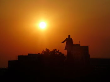 Low angle view of silhouette man standing against orange sky