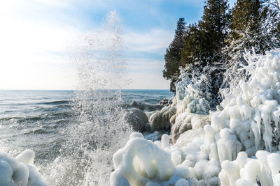 Sea waves splashing on shore against sky