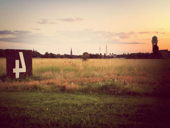 Scenic view of grassy field against sky at sunset