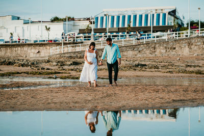 Rear view of couple walking on bridge over water