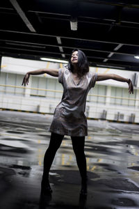 Full length of young woman standing on wet floor in parking lot