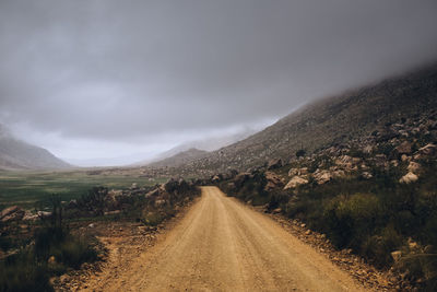 Dirt road along landscape against sky