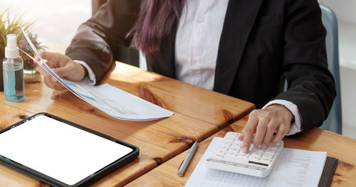 Midsection of woman using mobile phone while sitting on table