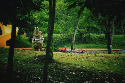 Woman carrying grass in wheelbarrow at park