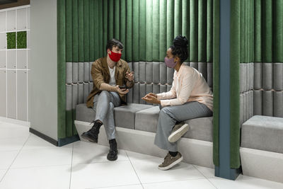 Business people in protective face mask planning while sitting on sofa at work place