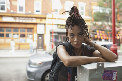 A young woman leaning against a metal box.