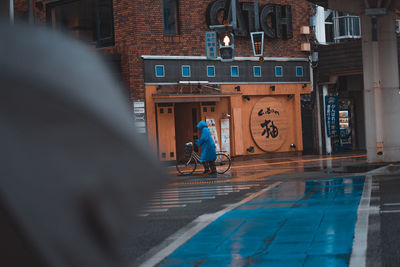 Man riding bicycle on street against buildings in city