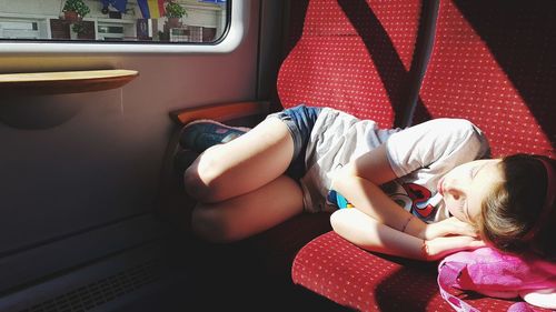 Full length of girl sleeping on seat in train