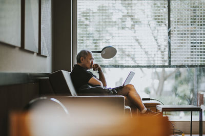 Young man using mobile phone while sitting on chair