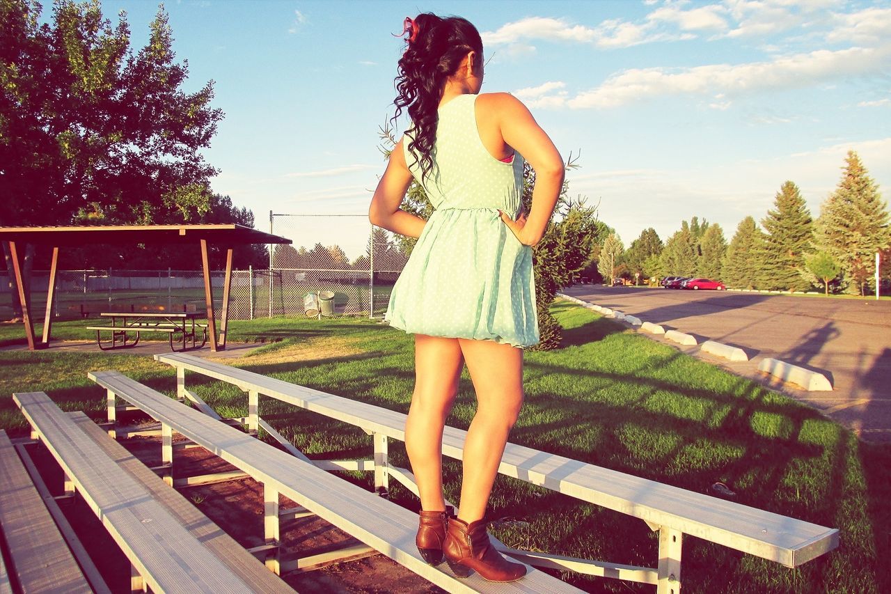 lifestyles, full length, leisure activity, casual clothing, young adult, person, tree, young women, standing, sky, railing, enjoyment, carefree, dress, front view, sunlight, arms outstretched, outdoors