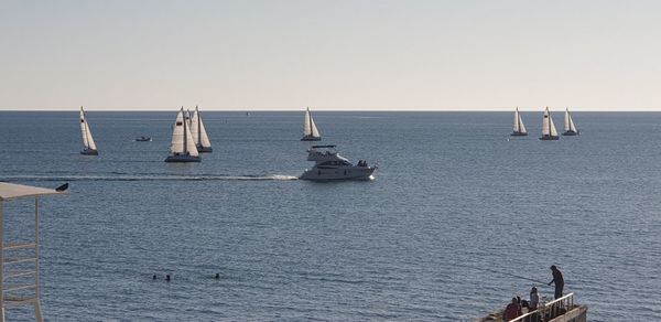 Sailboats sailing in sea against clear sky