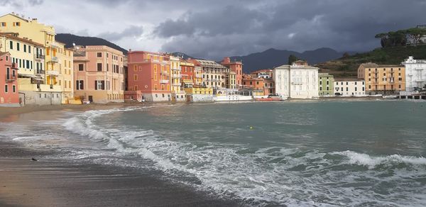 Buildings by sea against sky