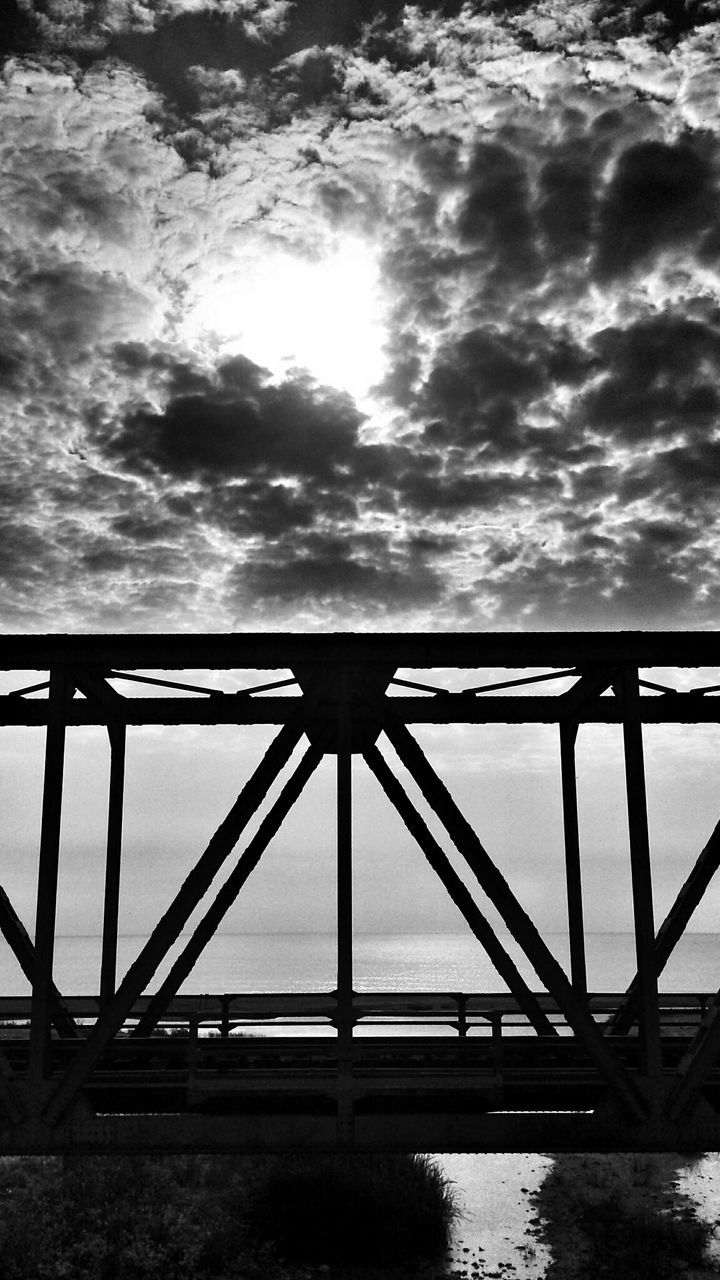 sky, cloud - sky, water, connection, cloudy, built structure, bridge - man made structure, architecture, sea, railing, cloud, low angle view, bridge, weather, nature, overcast, tranquility, silhouette, engineering, sunset