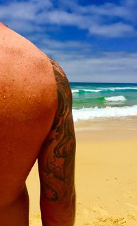 Midsection of man on beach against sky