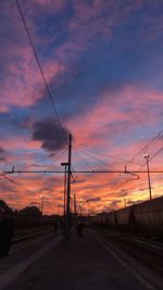 Railroad tracks against dramatic sky during sunset