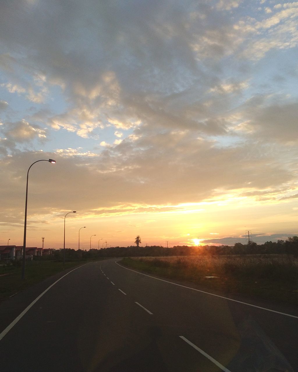 sky, sunset, transportation, road, cloud, nature, horizon, street, dawn, no people, highway, mode of transportation, travel, sign, city, marking, car, symbol, the way forward, sun, road marking, outdoors, sunlight, street light, environment, beauty in nature, afterglow, dramatic sky, motor vehicle, diminishing perspective, scenics - nature, evening, vanishing point, landscape, orange color, infrastructure, tranquility, travel destinations