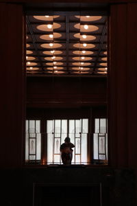 Rear view of man sitting on window