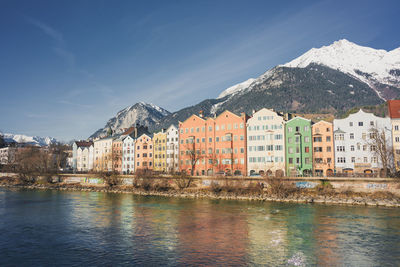 Buildings by river against sky