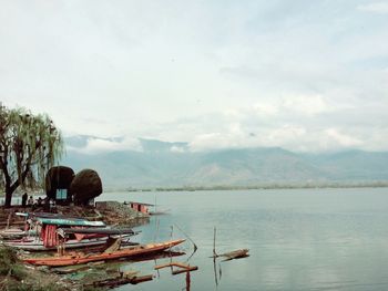 Boats moored in lake against sky