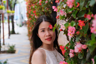 Portrait of young woman standing by plants
