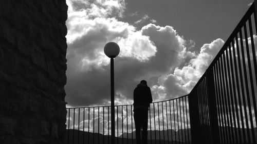 Low angle view of people standing against cloudy sky