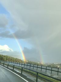 Rainbow over road against sky