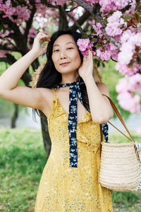 Portrait of smiling young woman standing against plants