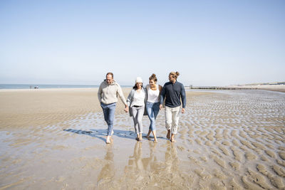 People on beach against clear sky