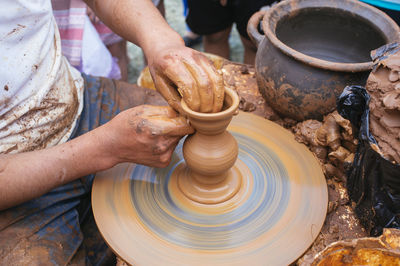 Close-up of man shaping pottery clay on wheel