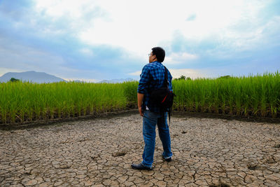 Rear view of man standing on field against sky