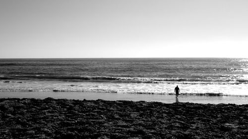 Silhouette man standing on beach against clear sky