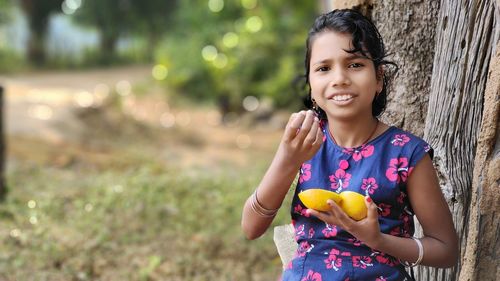 Little girl playing with fresh orange. blurred green background, copy space