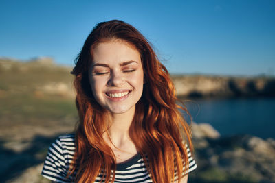 Portrait of smiling young woman against sky