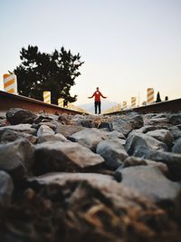 Man standing on rock against sky during sunset