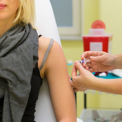 Cropped hand of doctor giving syringe to patient