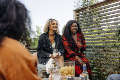 Happy female friends with drinks enjoying during dinner party