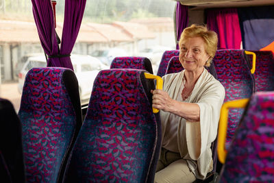 Senior woman sitting on travel bus and waiting for excursion