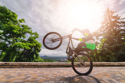 Young cyclist rides a wheelie. biker balances while riding a mountain bike. risky riding on one