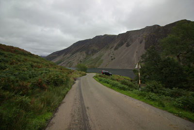 Road amidst green mountains against sky