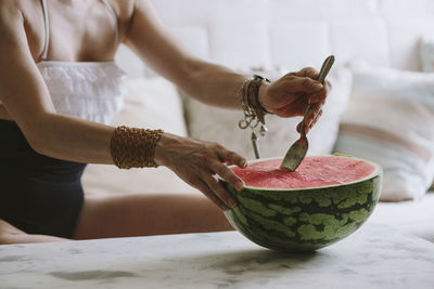 Midsection of woman eating watermelon on table