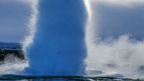 Geyser erupting against sky